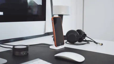 Desk with a monitor, a phone on a dock, headphones and a mouse
