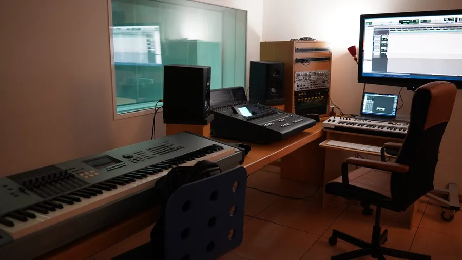 Studio desk with monitors, a synthesizer keyboard and an office chair