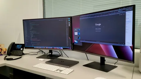 Two monitors side by side on a white desk with a keyboard and mouse