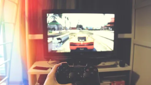 Player holding a controller in front of a screen showing a racing game