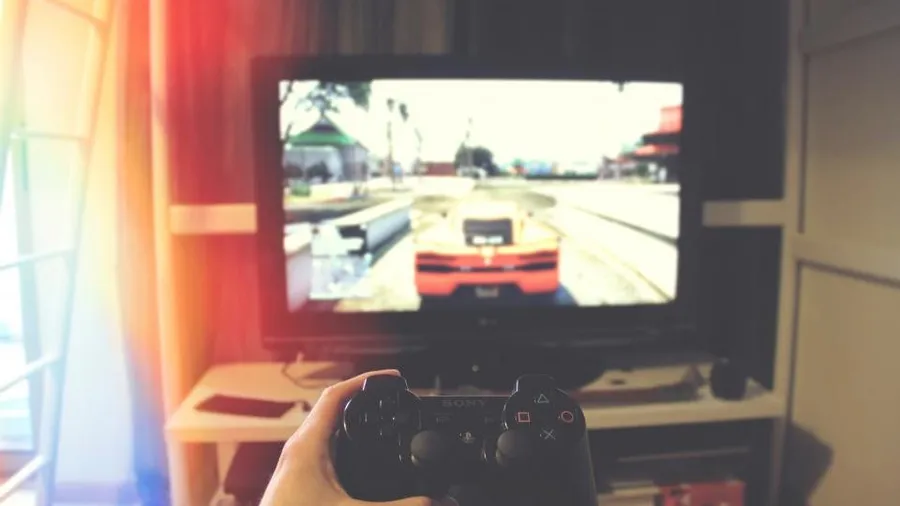 Player holding a controller in front of a screen showing a racing game