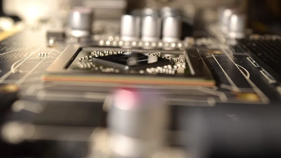 Close-up of a graphics processor chip on a graphics card circuit board, surrounded by small components and capacitors