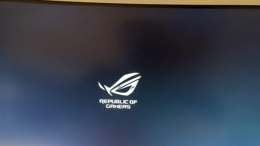 Curved ASUS ROG gaming monitor showing its startup logo, with FreeSync 2 HDR and HDMI badges in the corner