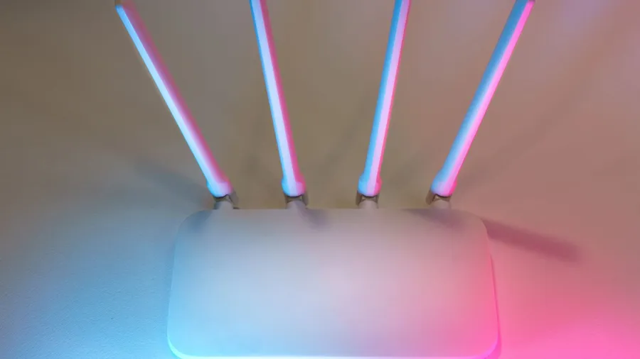 A modern wireless router with antennas lit by colored ambient light