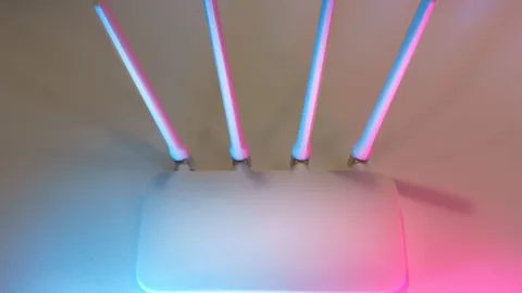 A modern wireless router with antennas lit by colored ambient light