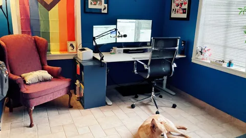 Home office with a desk, two monitors, an office chair, an armchair and a dog lying on the floor