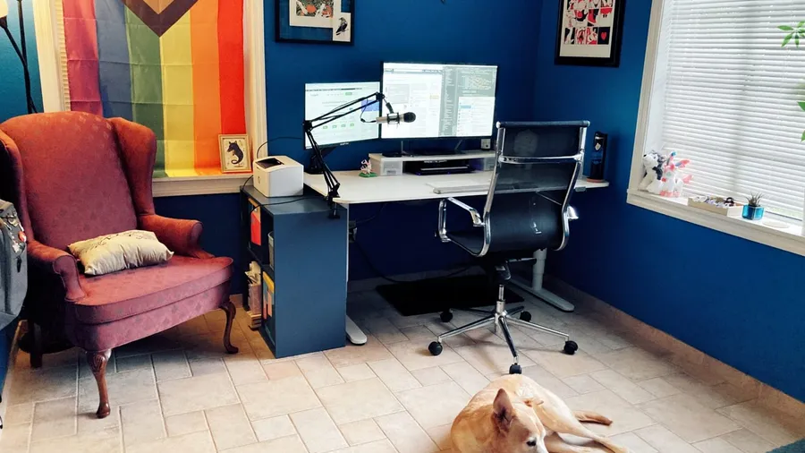 Home office with a desk, two monitors, an office chair, an armchair and a dog lying on the floor