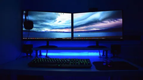 Two flat-screen computer monitors turned on side by side on a desk