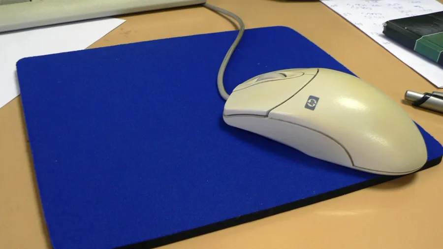 Wired mouse on a blue cloth mouse pad on a desk