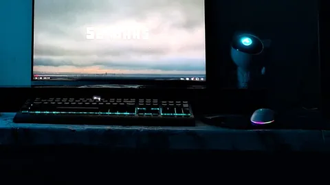 Backlit gaming keyboard and RGB mouse on a desk mat in a dim room