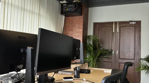 Desk with two black monitors and an office chair in a bright room