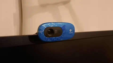 Blue patterned Logitech webcam clipped to the top edge of a computer monitor
